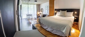 Une chambre moderne avec un grand lit, des lampes de chevet et une vue sur la salle à manger.