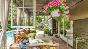 Un espace extérieur aménagé, abrité et doté d'une piscine, de meubles en osier et de suspensions florales.