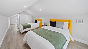 A bedroom with two beds, white walls, and a sloped ceiling. - Modern Chic Retreat in the Heart of EaDo, Houston (Houston)