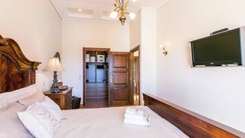 Une chambre d’hôtel bien rangée, avec un lit, une télévision, une tête de lit en bois, une lampe et une armoire.