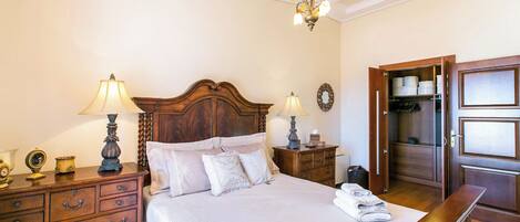A neatly arranged bedroom with a wooden bed, bedside lamps, a dresser, and a wardrobe.