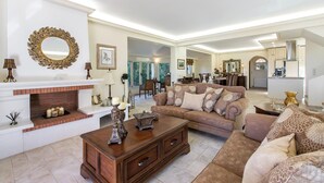 Ein geräumiges Wohnzimmer mit Kamin, einer Sofagarnitur und einem Essbereich im Hintergrund.