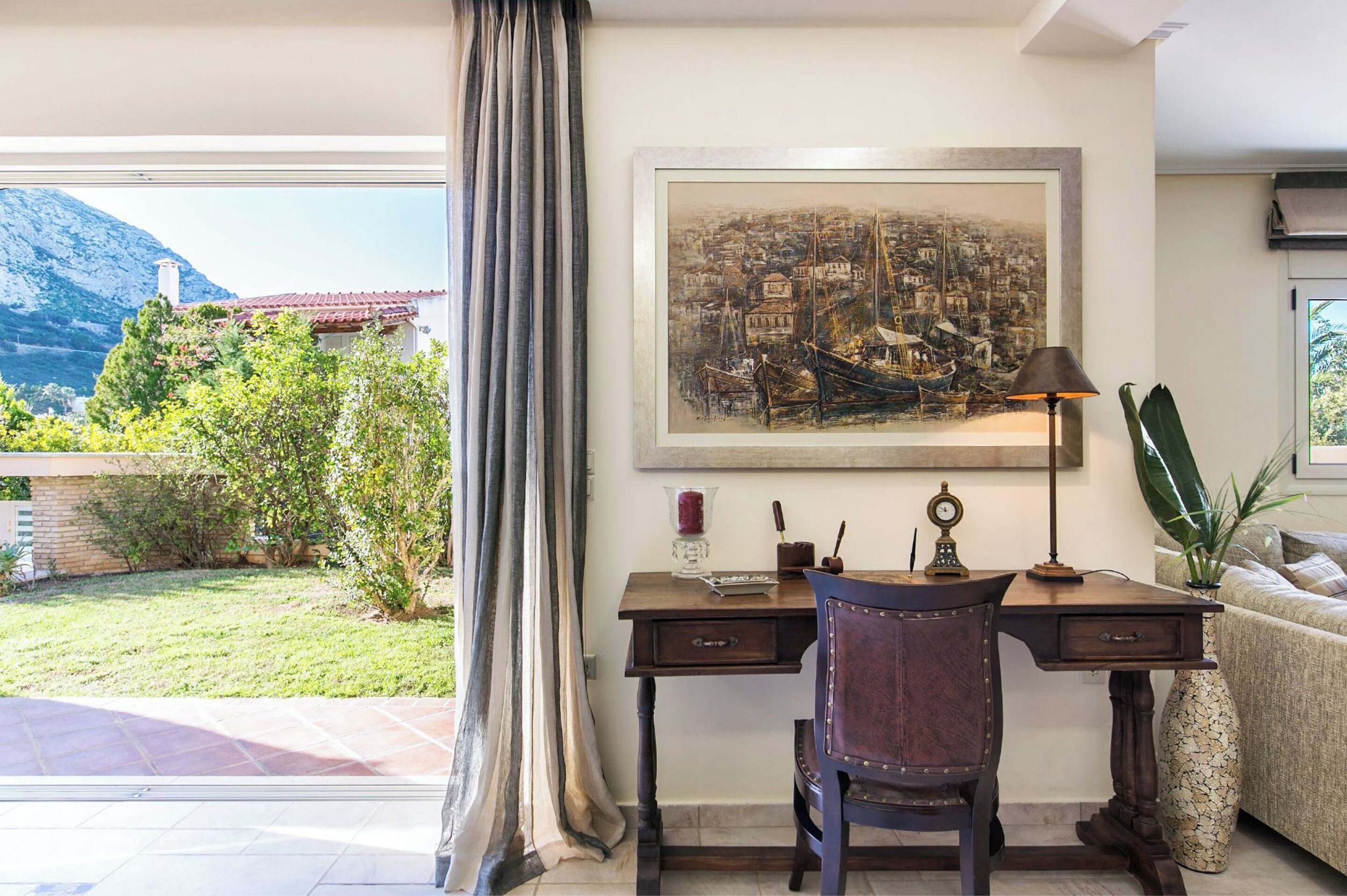 Una habitación con escritorio, silla y un cuadro grande de un pueblo costero.