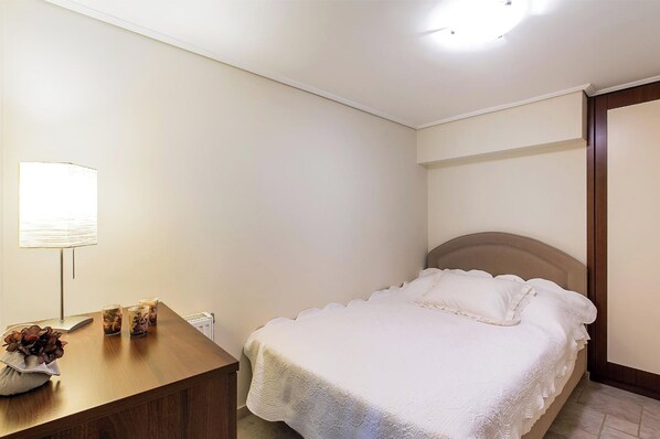A bedroom with a bed, a bedside table with a lamp, and a small decorative item. - Villa Melia Athenian Riviera (Saronikos)