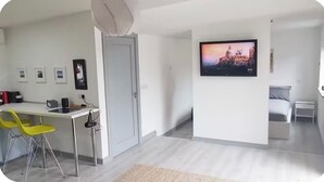 Una sala de estar moderna con un televisor de pantalla plana, un comedor con sillas amarillas y un sofá gris.