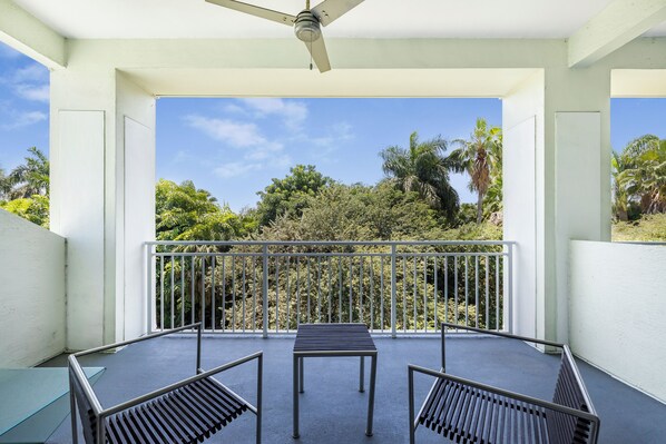 A balcony with a table and chairs, a ceiling fan, and a view of tropical foliage. - Two-Level Town House-Doral location-We Host (Miami)