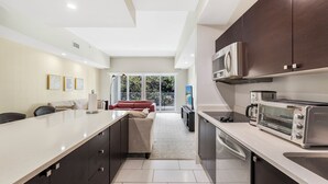 A modern kitchen with dark cabinets, a large island, a microwave, and a toaster oven. - Exclusive Doral Stay W Luxury Amenities (Miami)