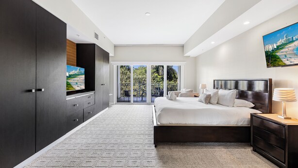 A modern bedroom with a large bed, a TV, and a balcony with a city view. - Exclusive Doral Stay W Luxury Amenities (Miami)