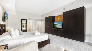 A modern hotel room with a large bed, a flat-screen TV mounted on the wall, and a dark wardrobe. - Exclusive Doral Stay W Luxury Amenities (Miami)