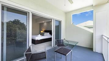 A balcony with a bed, two chairs, and a ceiling fan.