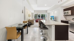 A modern kitchen with a central island, bar stools, and a dining area with chairs and a table. - Exclusive Doral Stay W Luxury Amenities (Miami)