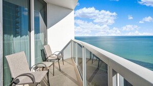 Un balcone con vista sull'oceano, dotato di una zona salotto con sedie e un tavolo.