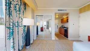 Une chambre d’hôtel avec un grand miroir, un lit, une lampe, une vue sur le couloir et un coin cuisine.