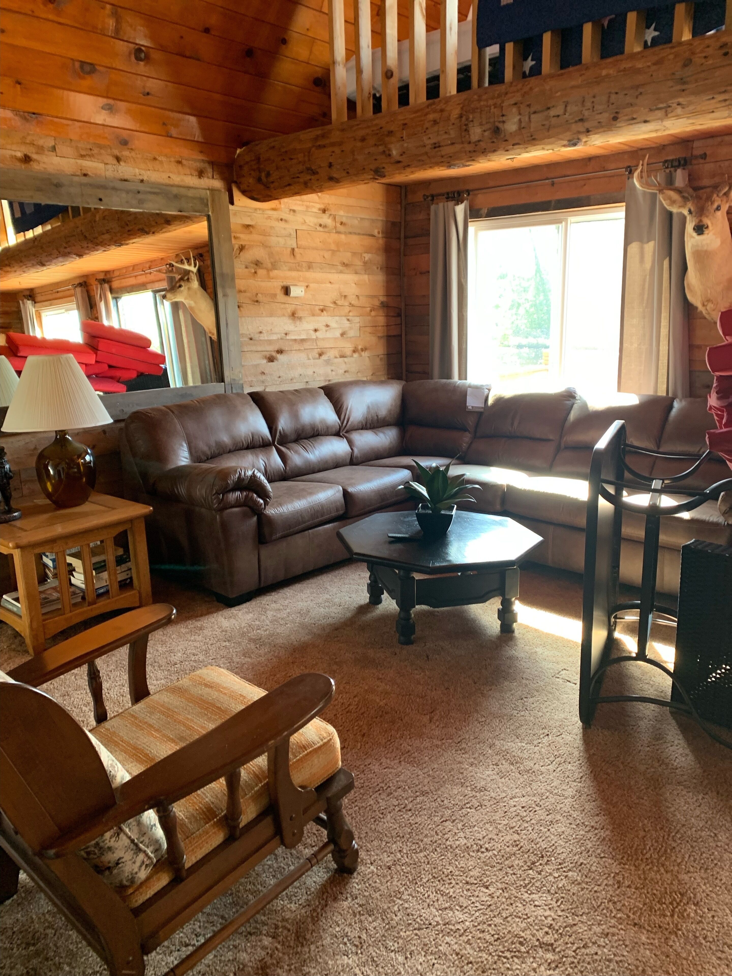 L’intérieur chaleureux d’un chalet avec un canapé d’angle en cuir marron, une table basse en bois et une chaise en bois.