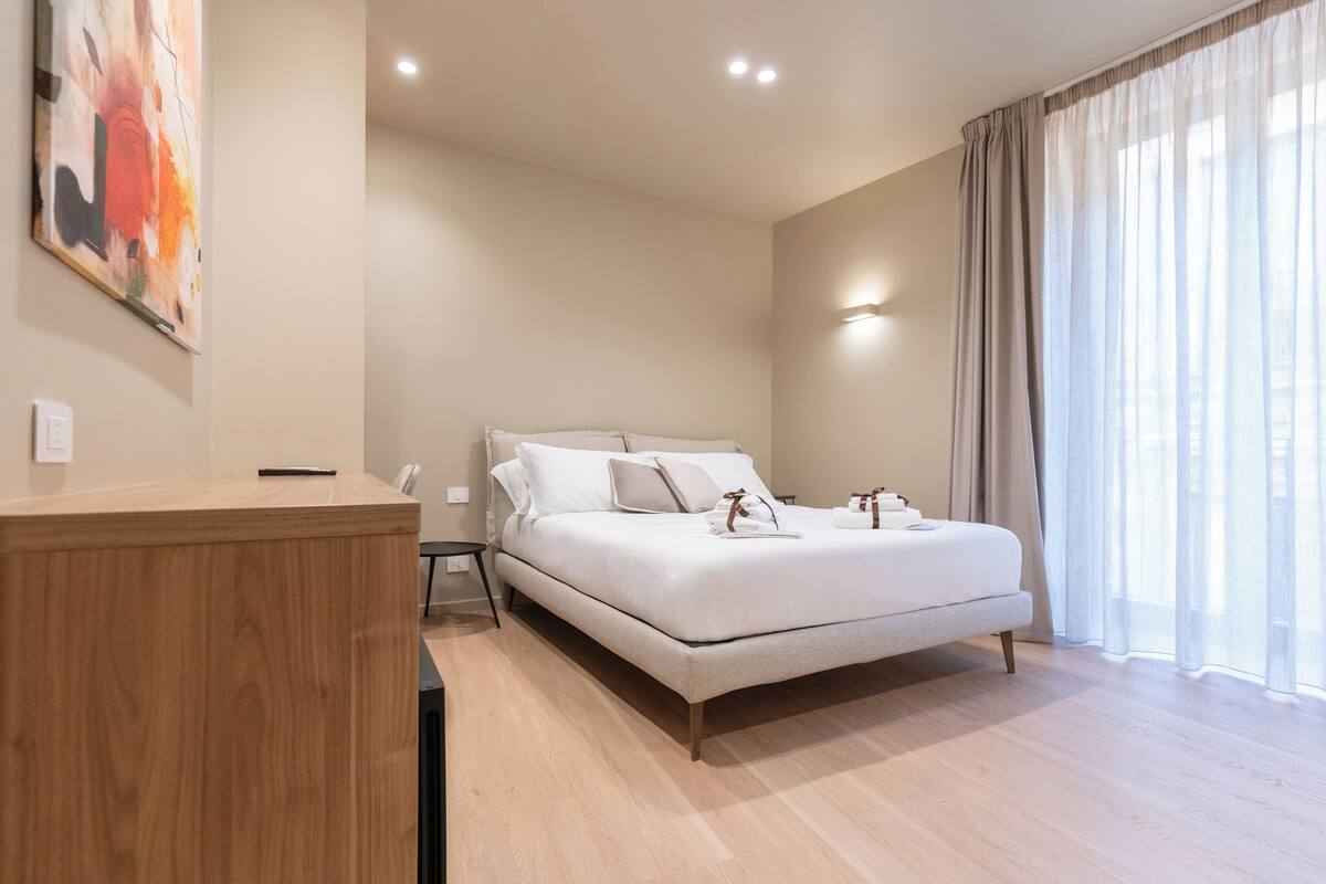 Ein modernes Schlafzimmer mit einem großen Bett, einem Holztisch und einem Gemälde an der Wand.