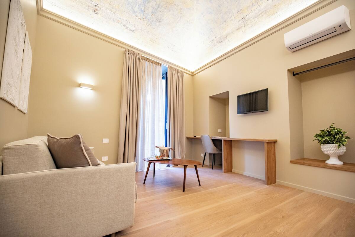 Ein modernes Wohnzimmer mit einer Couch, einem Holztisch, einem Schreibtisch und einem an der Wand befestigten Fernseher.