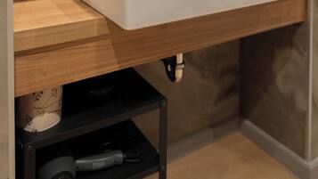 Un baño moderno con lavamanos blanco, encimera de madera y salpicadero de mármol.