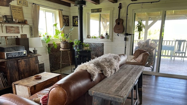 A rustic interior with a leather couch, wooden table, and a stone fireplace. - Driftless Log Cabin w/ Kickapoo Valley View (Readstown)