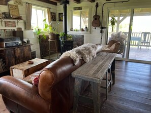 A rustic interior with a leather couch, wooden table, and a stone fireplace. - Driftless Log Cabin w/ Kickapoo Valley View (Readstown)