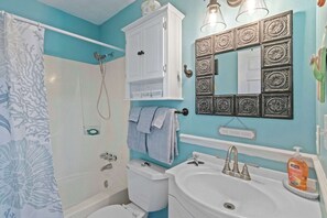 A bathroom with a shower, toilet, sink, and a cabinet with a mirror above it.