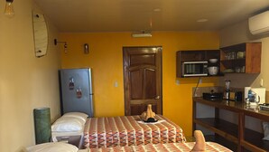Una habitación con dos camas, microondas, refrigerador y un armario de madera.