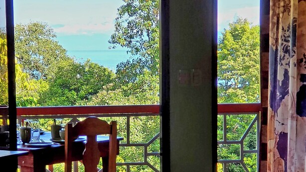 Un dormitorio con una cama, una silla y una mesa con vistas al exterior.