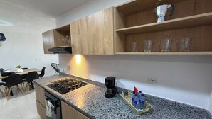 A kitchen with a granite countertop, a coffee maker, and a tray with bottles. - Modern Apartment with a Spectacular Ocean View (Santa Marta)