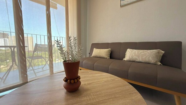 Una sala moderna con un sofá marrón, una mesa de centro de madera y una planta en maceta.