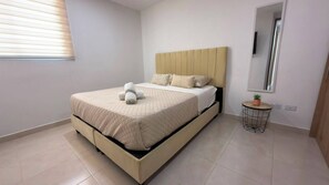 Un dormitorio con cama, una mesita de noche con una planta y un espejo en la pared.