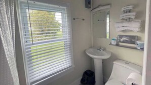 Un baño con ventana, lavamanos, inodoro y toallero.