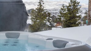 Un bain à remous avec vue sur les montagnes et les arbres enneigés.