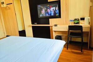 Une chambre d’hôtel équipée d’un lit, d’un bureau, d’une chaise, d’une télévision et d’une machine à café.