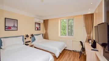Habitación de hotel con dos camas, un escritorio con computadora, un televisor y una ventana con cortinas.