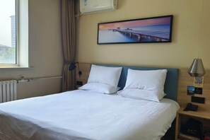 Une chambre d’hôtel avec un lit, une table de chevet, une lampe et un tableau représentant une jetée accroché au mur.