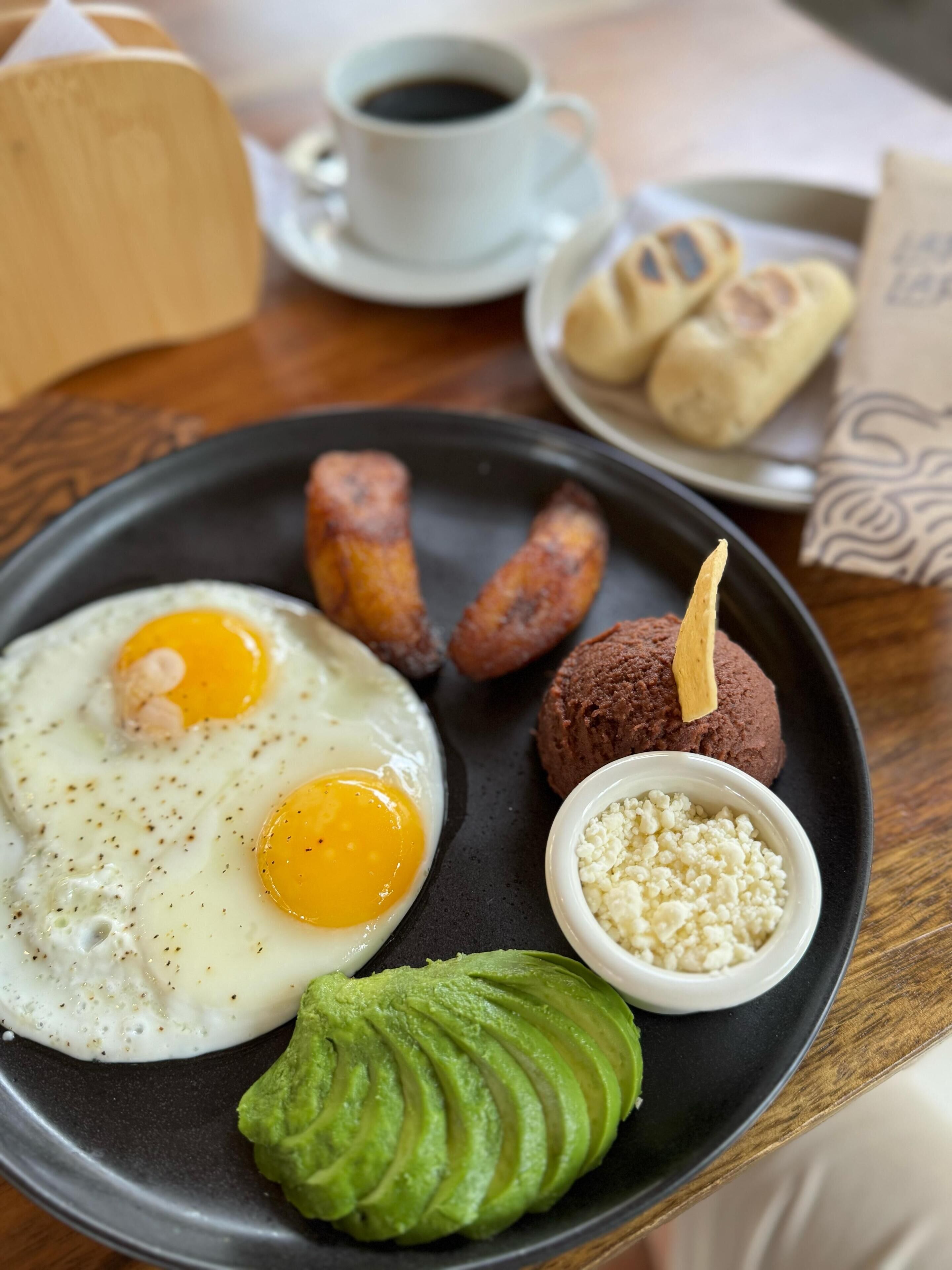 A breakfast plate with eggs, avocado, and sausages.