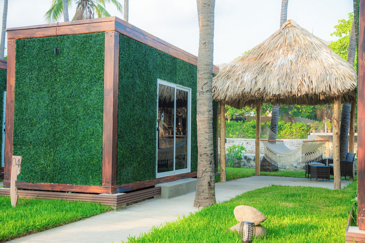Un edificio moderno con un muro cubierto de vegetación y una estructura de techo de paja.