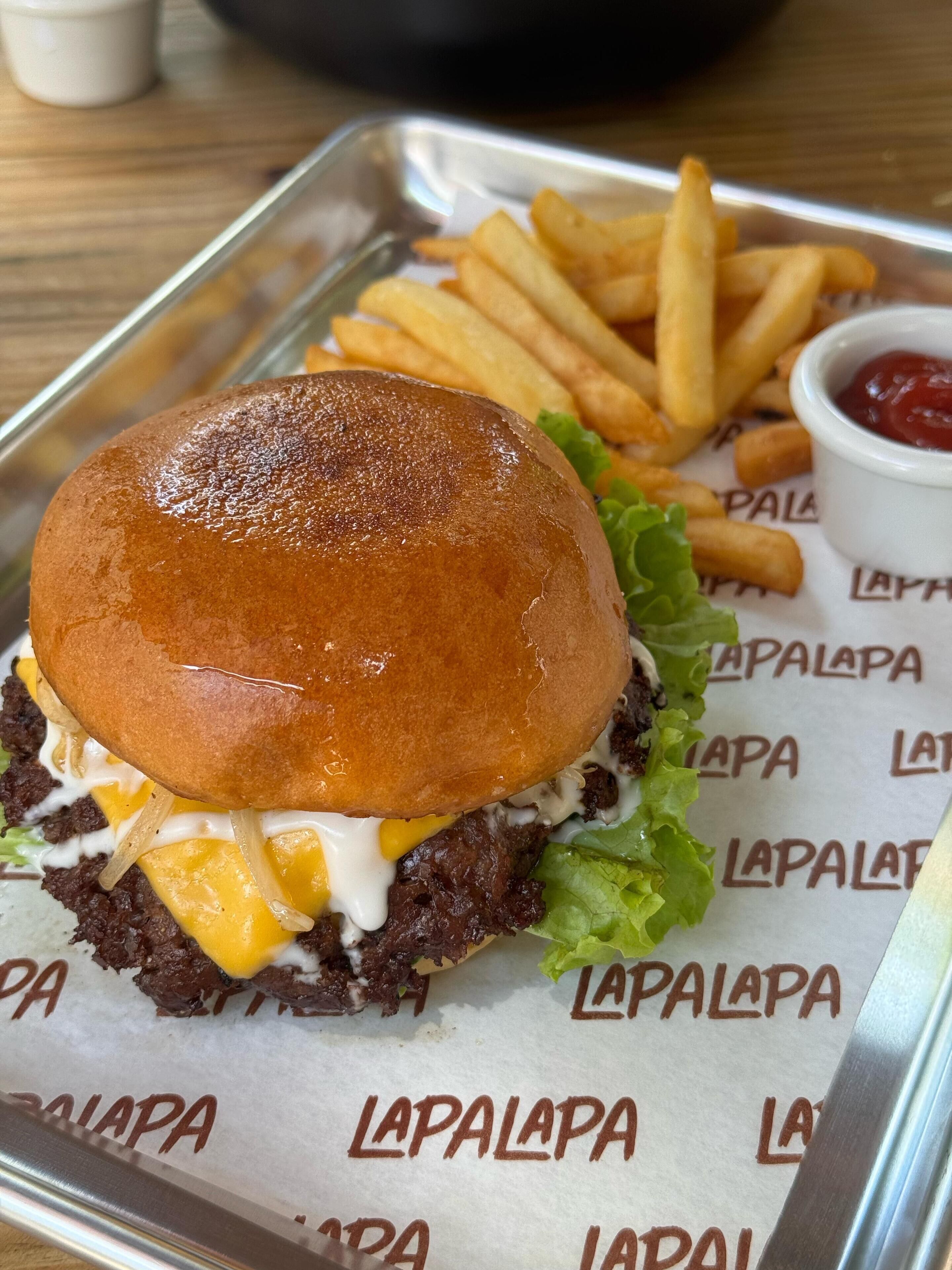 A burger with fries and ketchup on a tray.