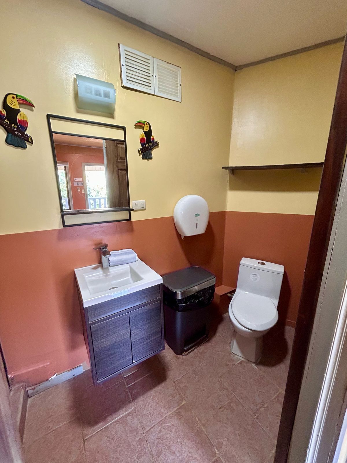 A compact bathroom with a sink, toilet, and a hand dryer.
