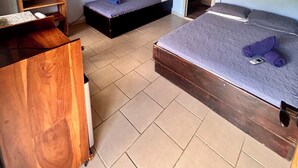 Une chambre avec deux lits, un bureau en bois et une petite étagère.