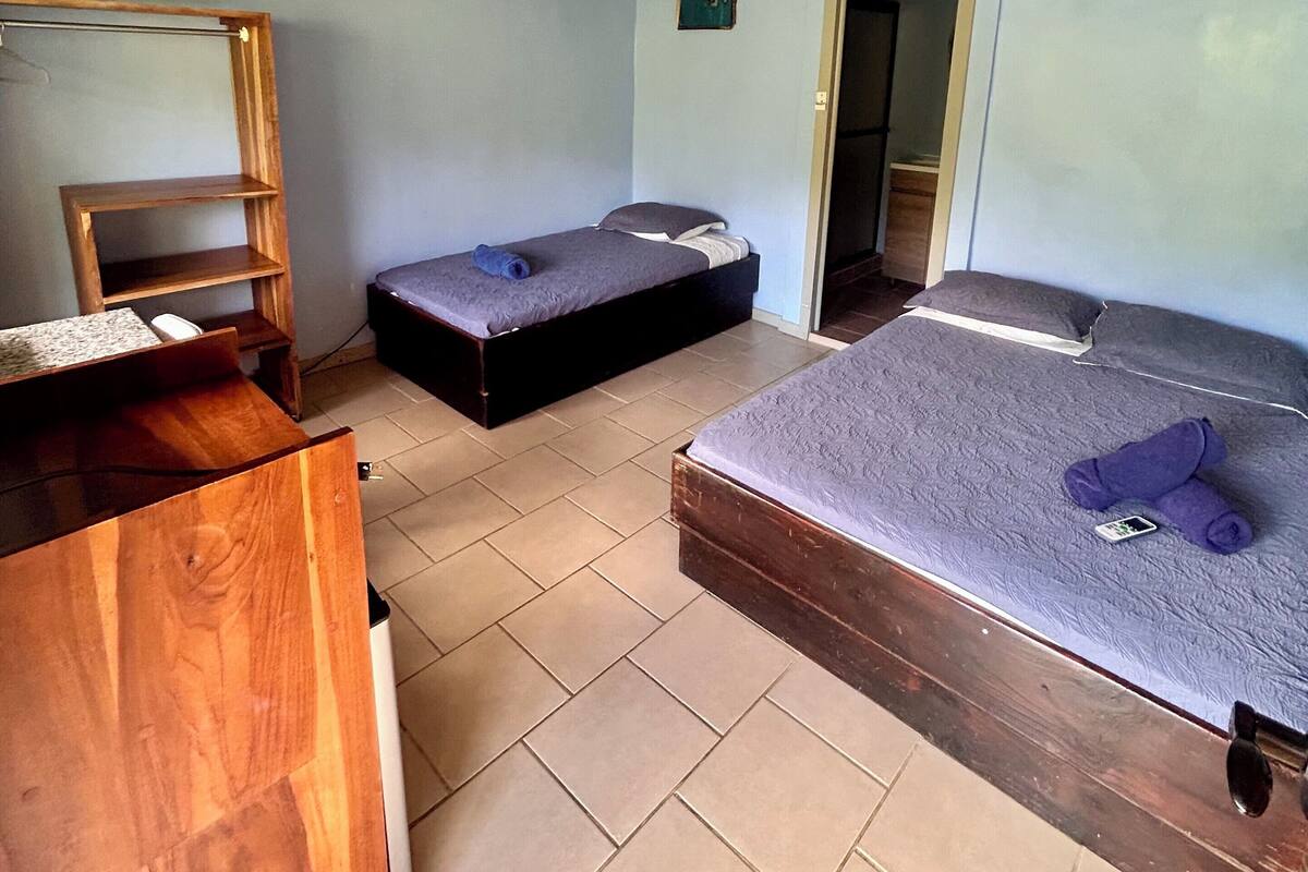 A room with two beds, a wooden desk, and a small shelf.