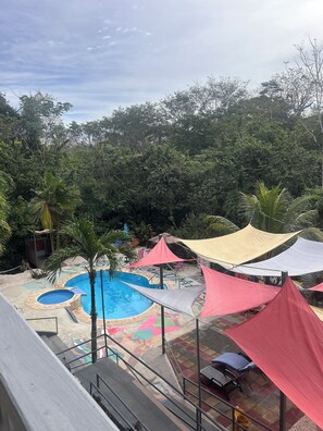 A pool area with multiple pools, shaded by colorful canopies, surrounded by lush greenery. - HOTEL TICOZUMA (Cóbano)