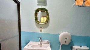 Une salle de bain équipée d’un lavabo, d’un miroir, de toilettes et d’un sèche-mains.