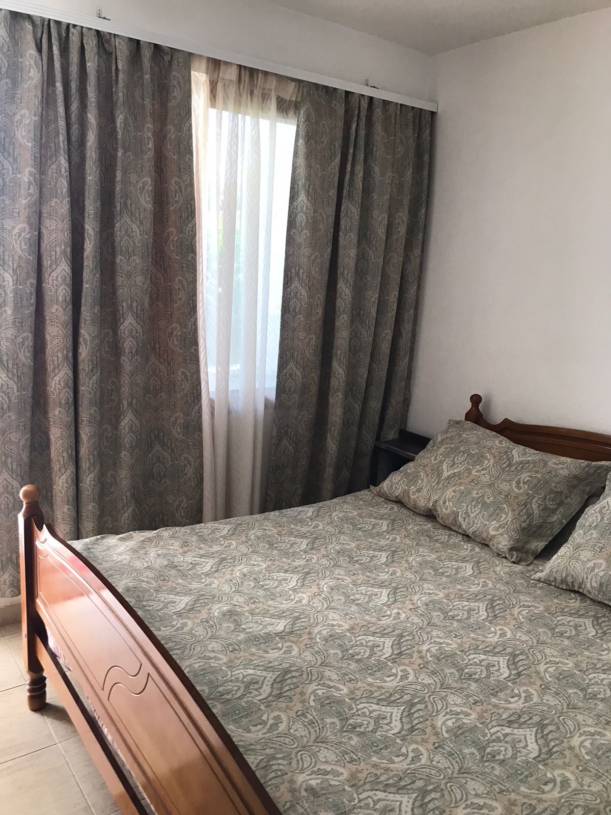 A bedroom with a bed, curtains, and a window.