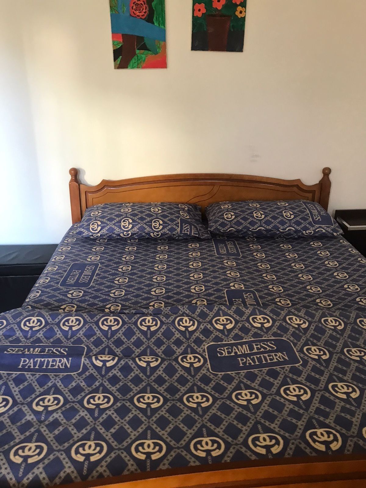 Cama com colcha e almofadas em padrão azul e dourado.