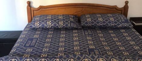 A bed with a blue and gold seamless pattern bedspread and matching pillows.