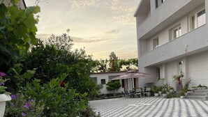 A courtyard with a checkered floor, surrounded by greenery and potted plants. - VILA CANO (Durrës)