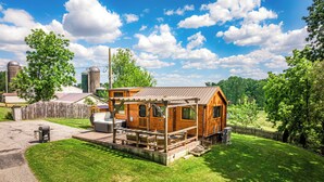 A small wooden cabin with a porch, a barbecue grill, and a picnic table. - Charming 2-bedroom tiny cabin hot tub camp fire sauna (Christiana)