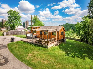 A small wooden cabin with a porch, a barbecue grill, and a picnic table.