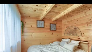 A wooden room with a bed, two wall-mounted decorative items, and a ceiling fan.