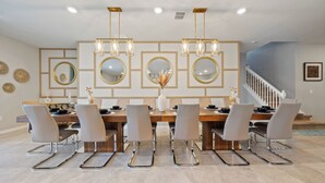 A dining area with a wooden table, six chairs, and a chandelier. - 9-bedrooms ~ 25 Mins To Parks ~ Pool, Water Slides Hot Tub, Sauna, Mini Golf! (Davenport)